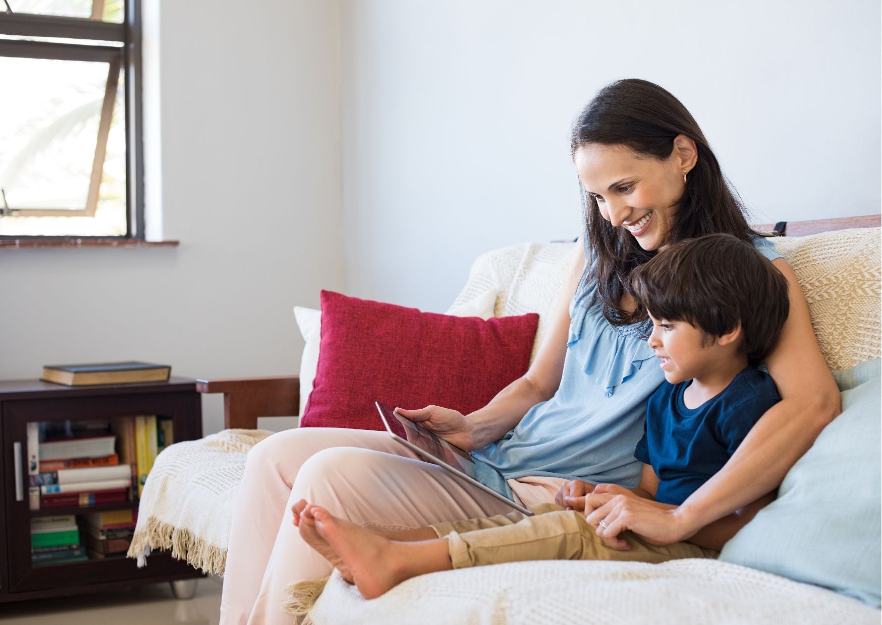 Mom and son sitting on a couch reading and smiling