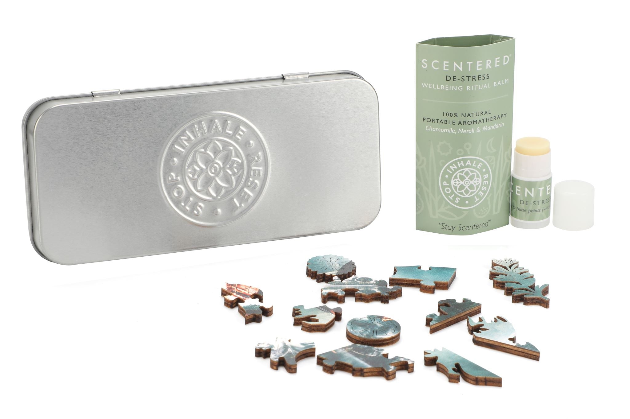 parts of puzzle laid in front of silver tin and Scentered De-stress Mini balm with cap off next to balm sleeve 