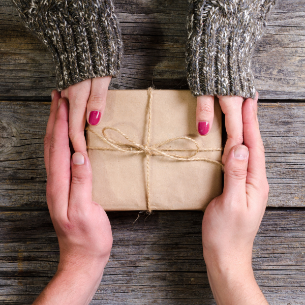 A wrapped present being exchanged between two people