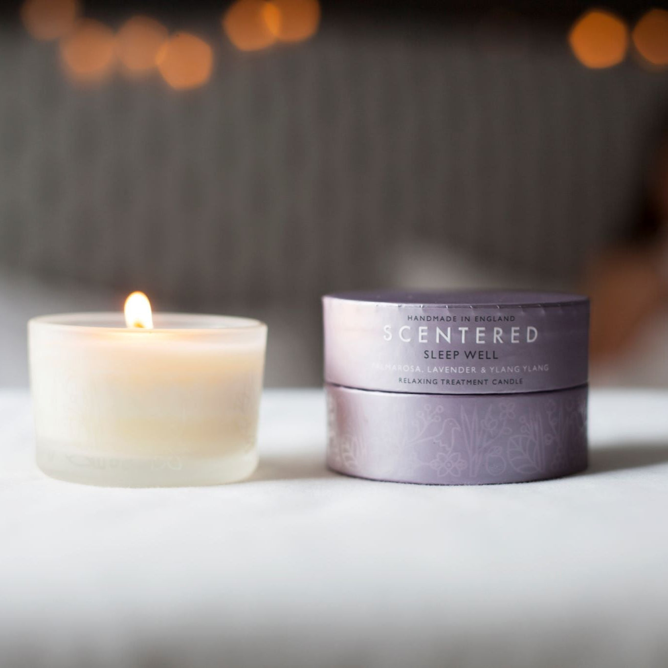 Scentered Sleep Well travel candle alit with person relaxing out of focus in the background